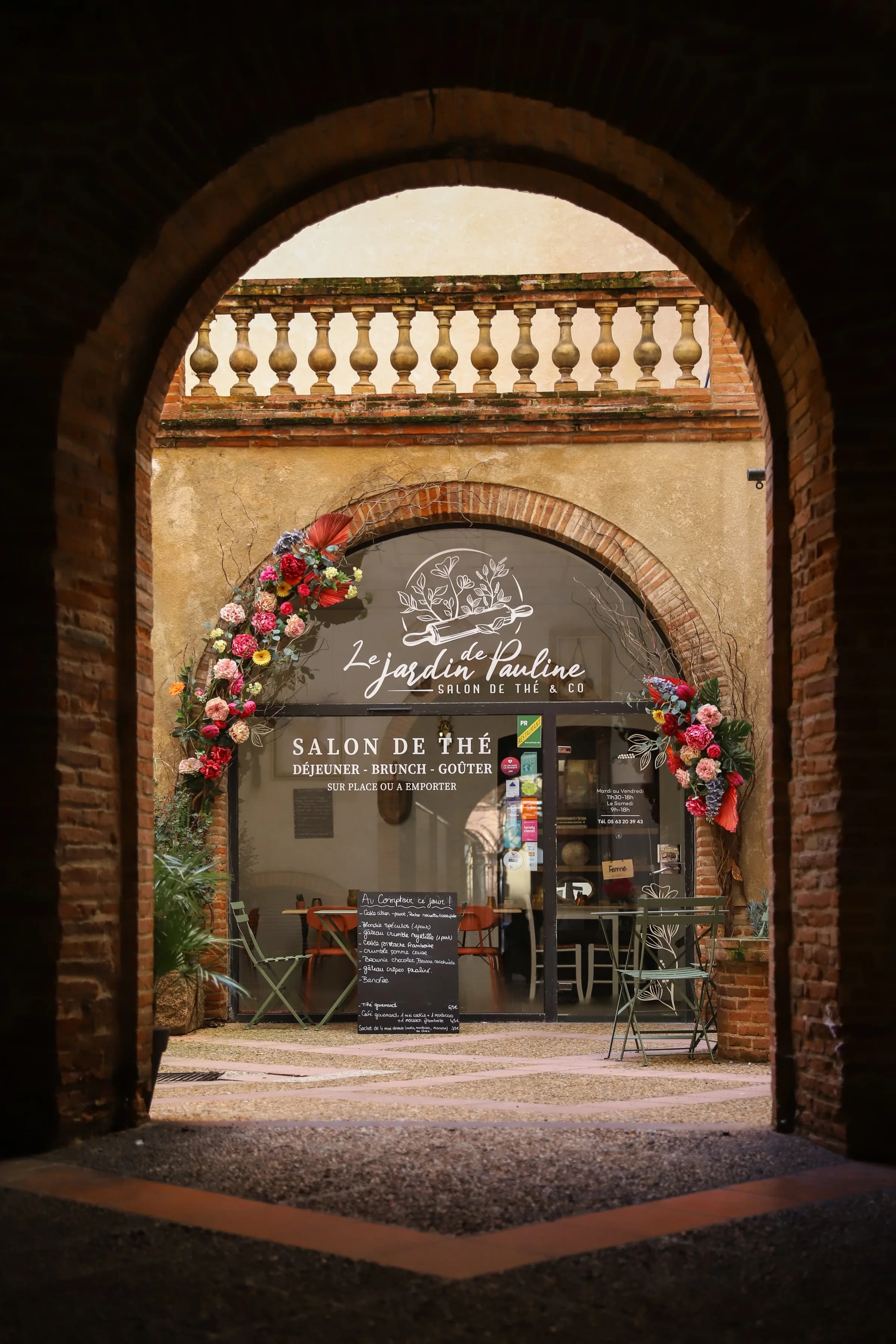 L'entrée fleurie du Jardin de Pauline sous une arche de briques